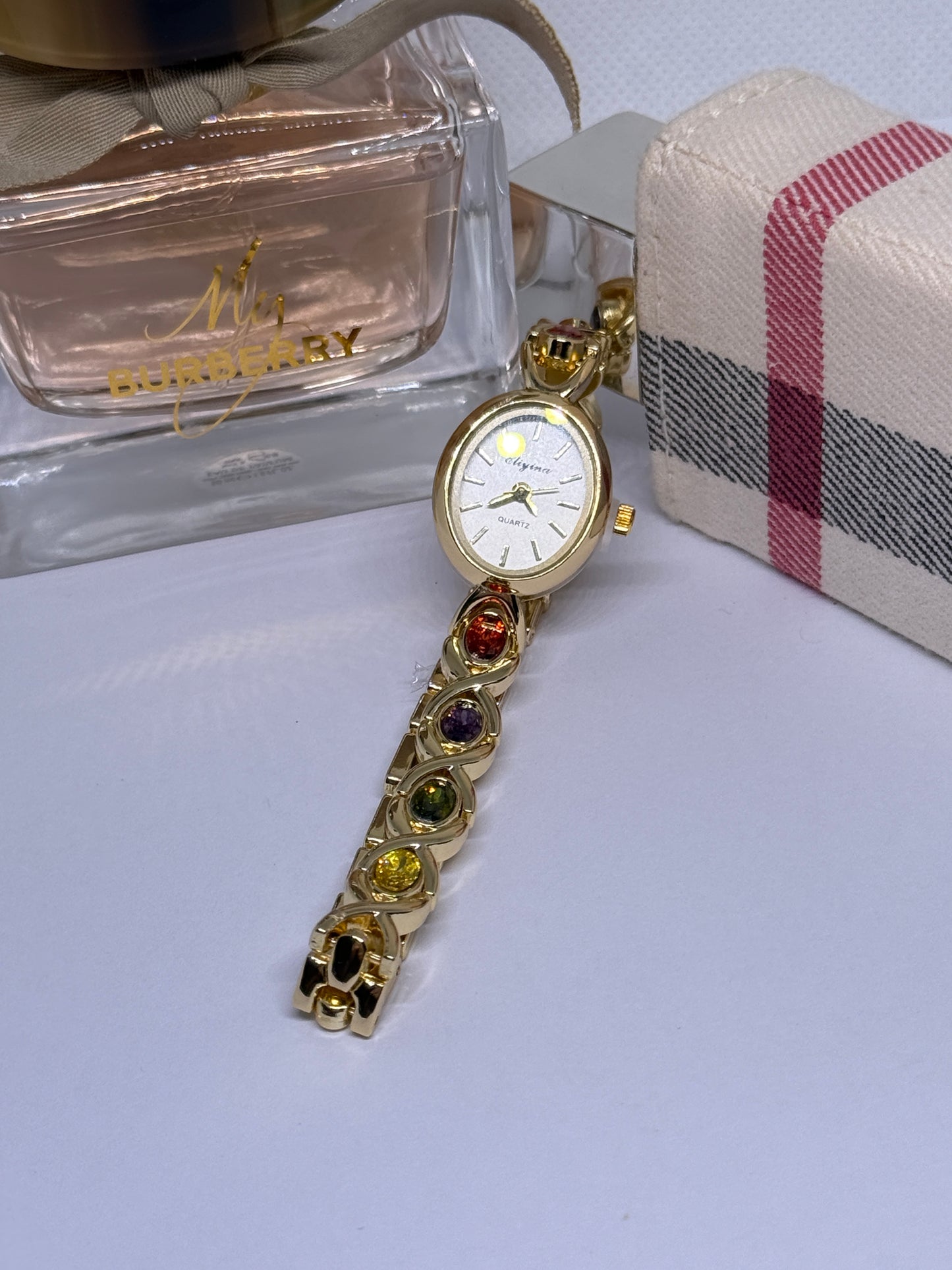 Gold tone watch with red, blue, and green stones