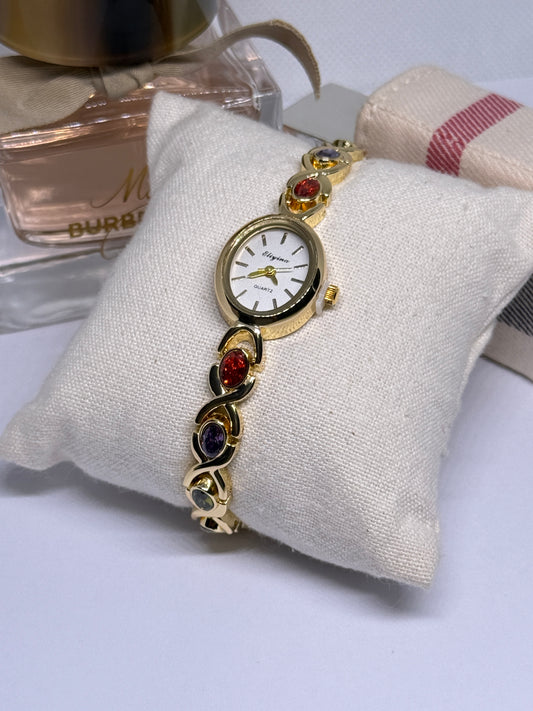 Gold tone watch with red, blue, and green stones