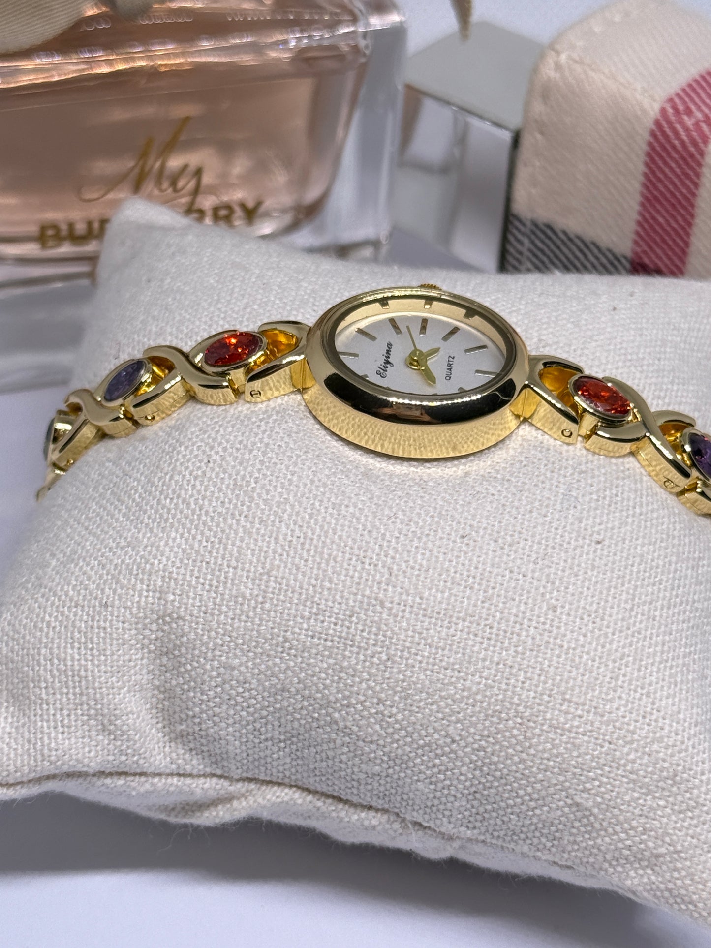 Gold tone watch with red, blue, and green stones