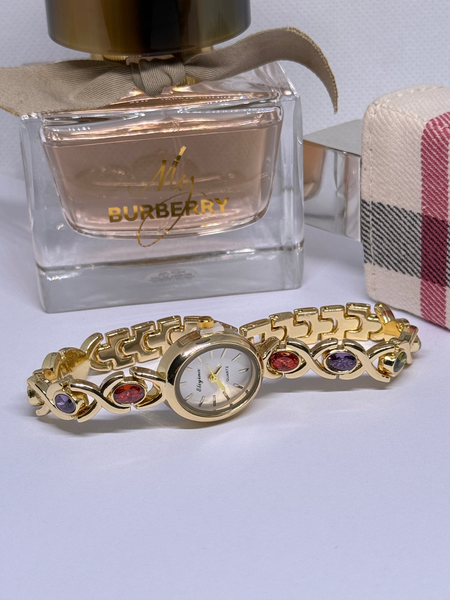 Gold tone watch with red, blue, and green stones