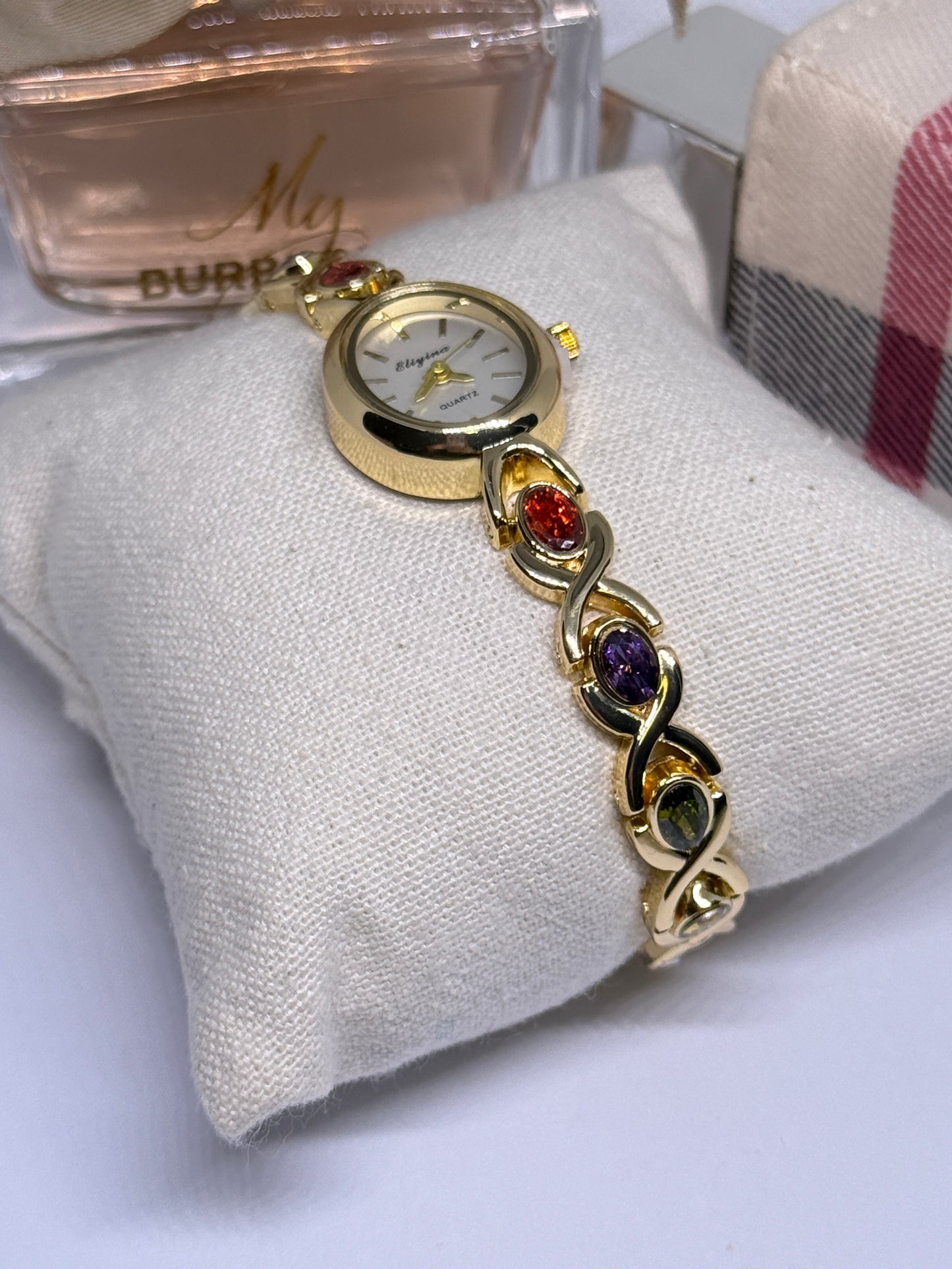 Gold tone watch with red, blue, and green stones